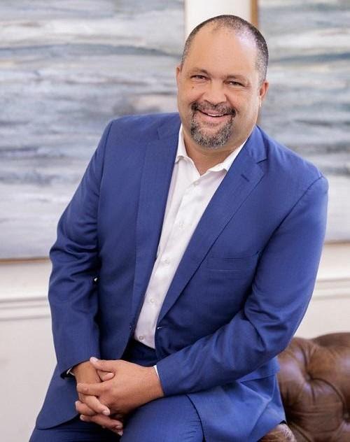 Ben Jealous is dressed in a blue suit and white collar shirt as he poses for portrait