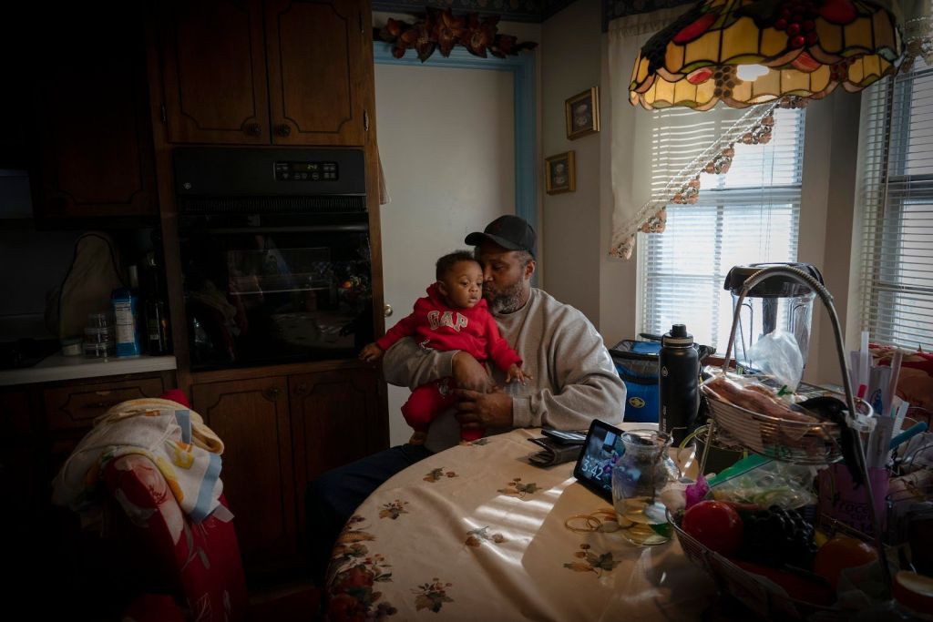 James Lyons kisses his grandson, Adrien Lyons, in the kitchen of his home in Birmingham, Ala.